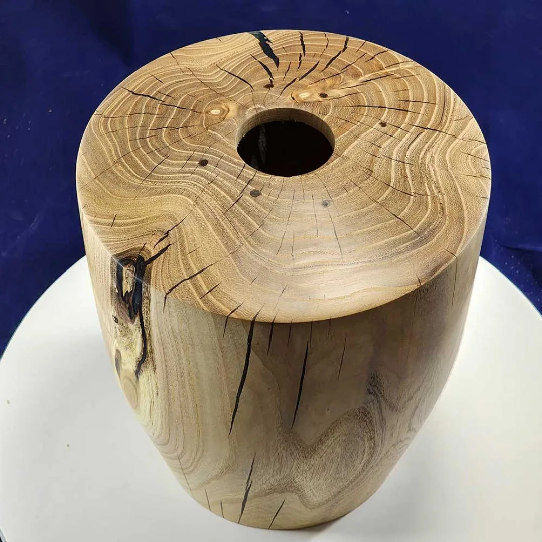 Ash urn, hand-turned with epoxy-filled spalting, on dark navy backdrop.